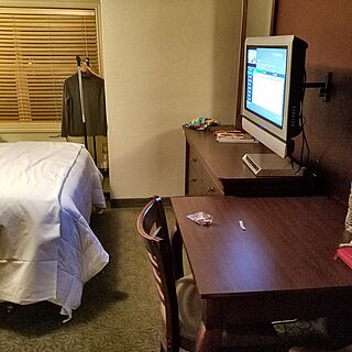 view of bed, TV, table and window which looks to pool area