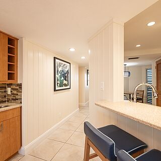 Kitchen counter with bar stools and wet bar with glassware and sink